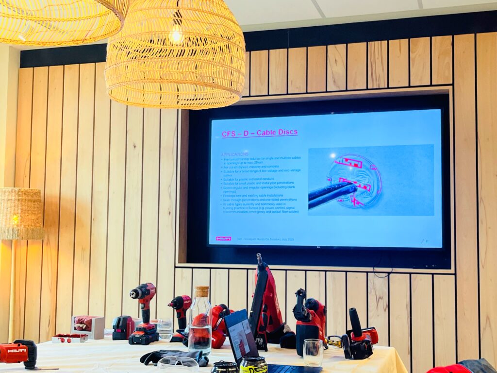 Image of lecture presentation slide on digital screen at front of class with Hilti tools that colleagues were being trained on in today's session neatly arranged on a table in front.